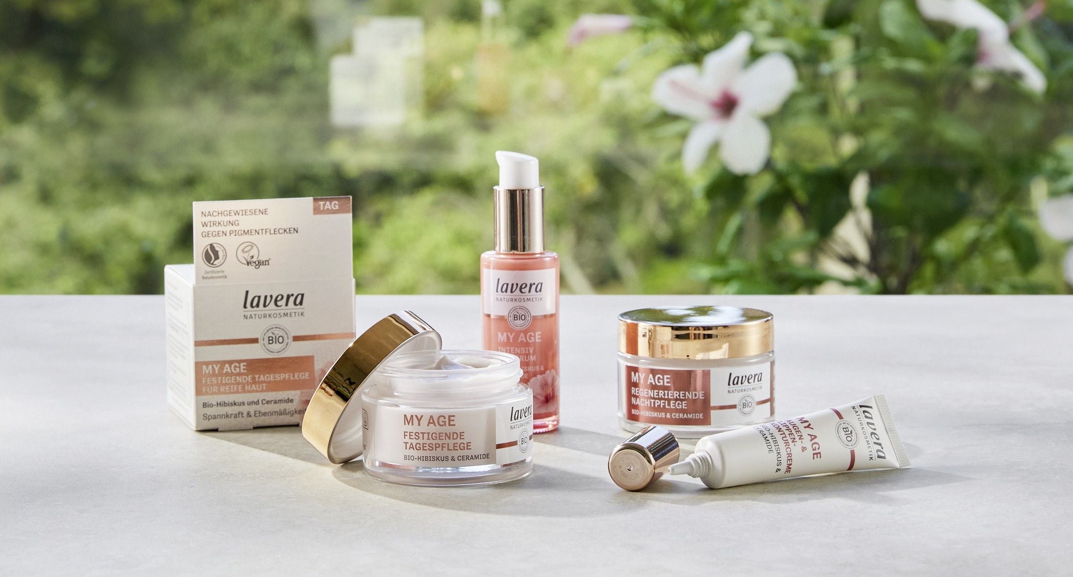 lavera My Age Produkt Range auf dem weißen Tisch mit Planzen im Hintergrund