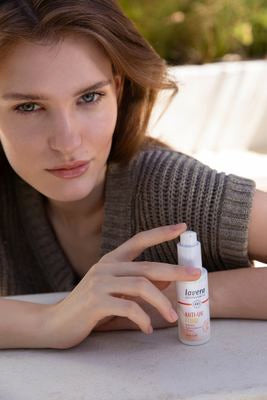 Frau präsentiert Anti-UV-Fluid im Garten