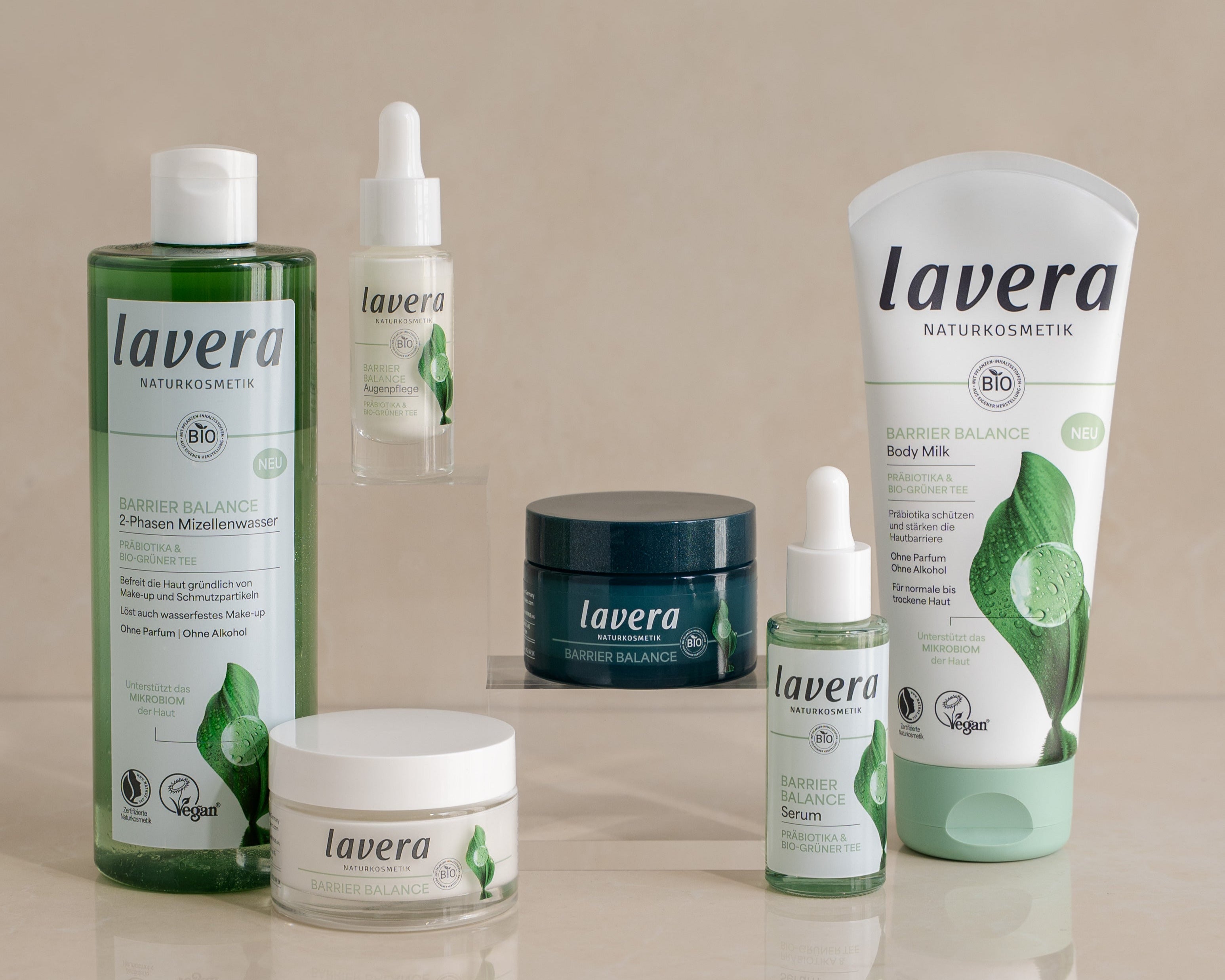 Sześć lavera kosmetyków naturalnych Barrier Balance: 2-fazowy płyn micelarny, krem pod oczy, krem, serum, mleczko do ciała i krem do twarzy na jasnym tle