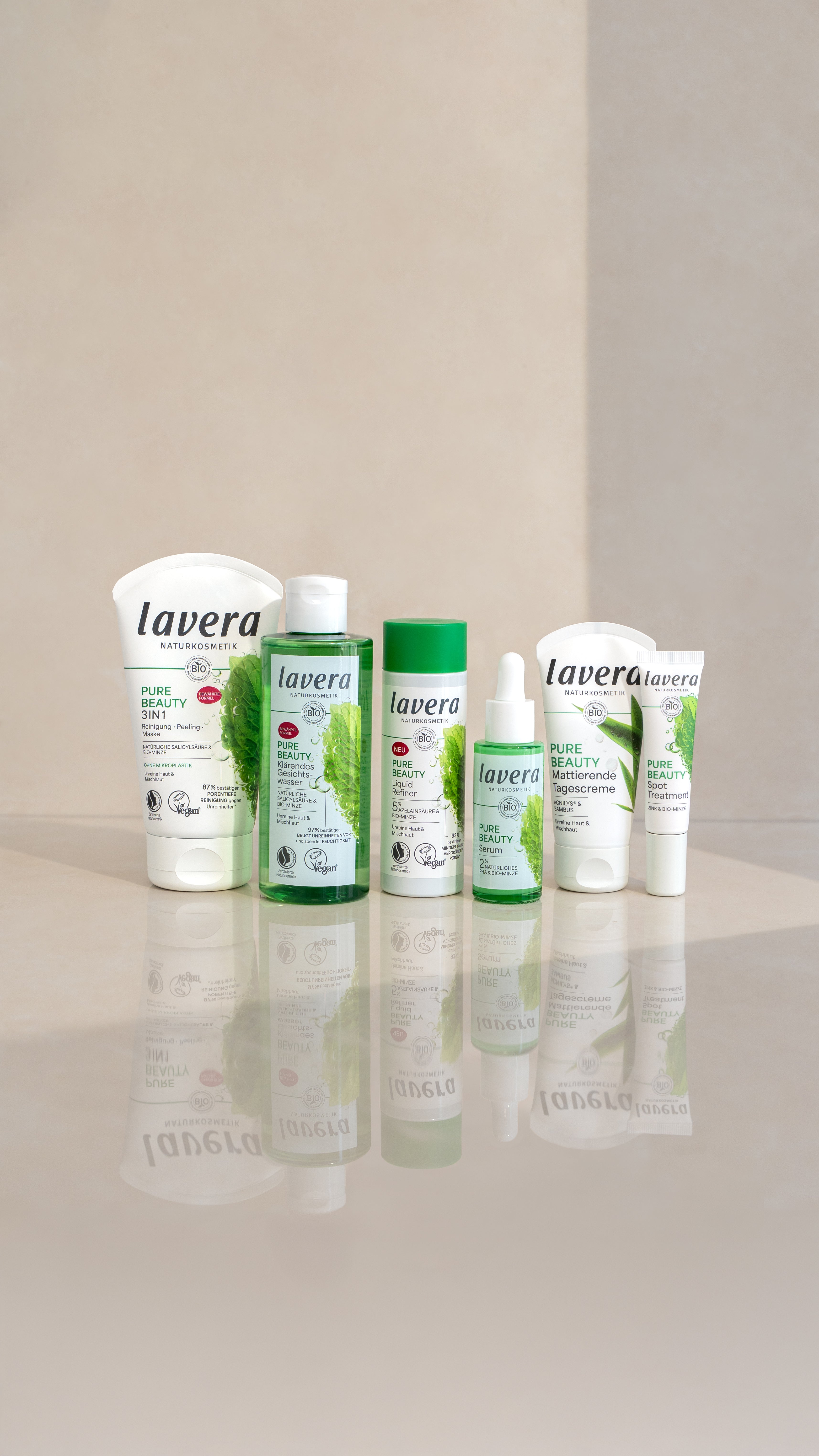 Sechs lavera Naturkosmetik Pure Beauty Produkte, aufgestellt auf hellem Untergrund, darunter Reinigung, Gesichtswasser, Serum, Tagescreme und Spot Treatment.