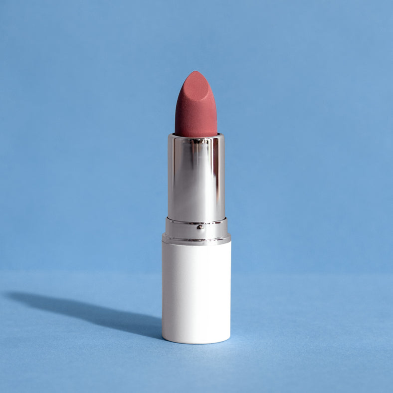 Rosa Lippenstift in silber-weißem Case vor blauem Hintergrund, Produktfoto