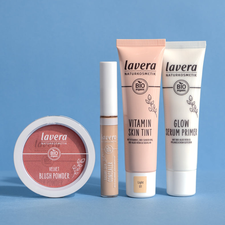 lavera Teintprodukte: Blush, Concealer, Skin Tint und Glow Primer vor blauem Hintergrund