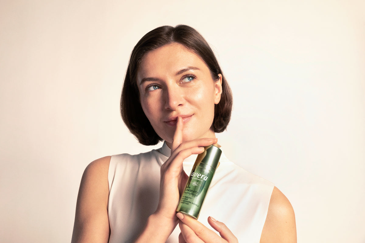 Frau mit braunen schulterlangen Haaren hält Skin Longevity Nachtpflege