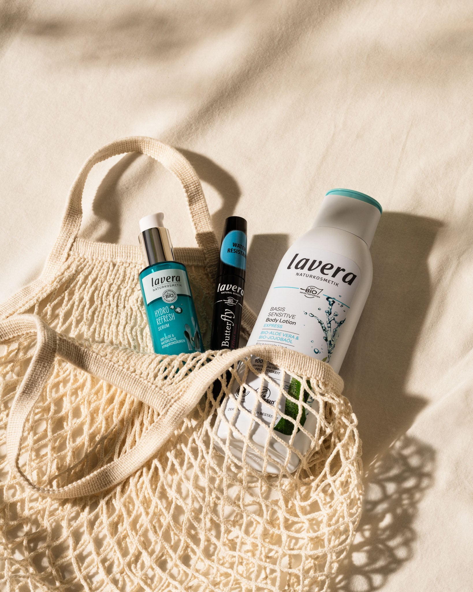 Ausgewählte lavera Produkte in einer Strandtasche vor einem beschen Hintergrund