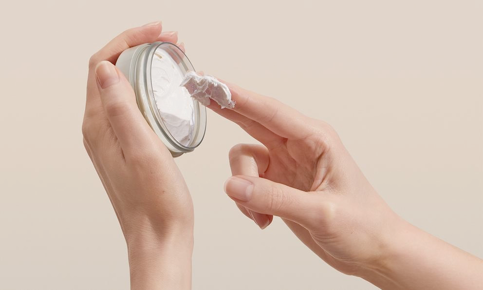Finger nimmt Creme aus Tiegel, Nahaufnahme der Textur