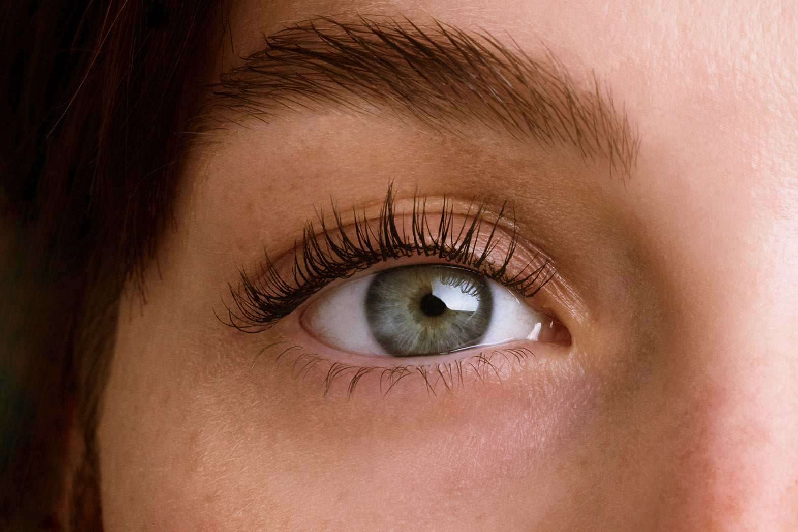 Detailaufnahme eines menschlichen Auges mit langen Wimpern und gepflegter Haut