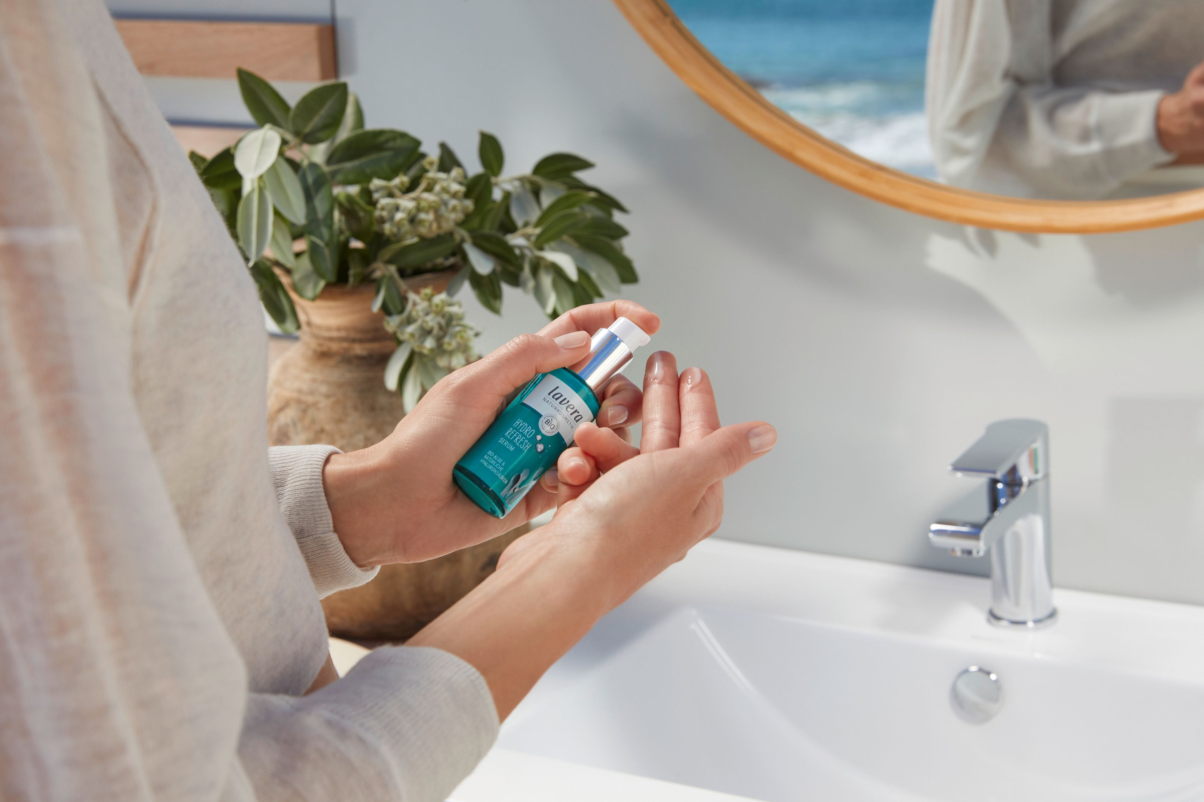 Frau im Bad trägt lavera hydro refresh serum auf die zwei Finger auf 
