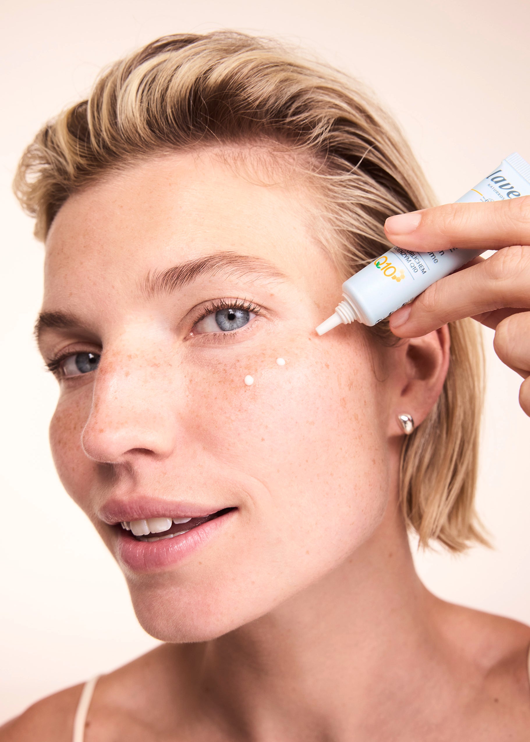 Frau trägt basis sensitiv Anti-Falten Augencreme Q10 auf das Gesicht auf 