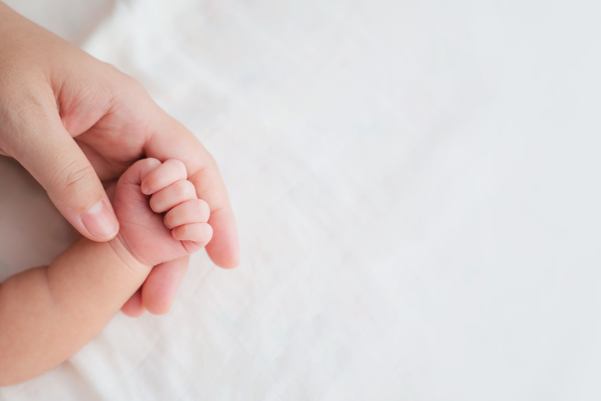 Ein Baby hält die Hand eines Erwachsenen fest.