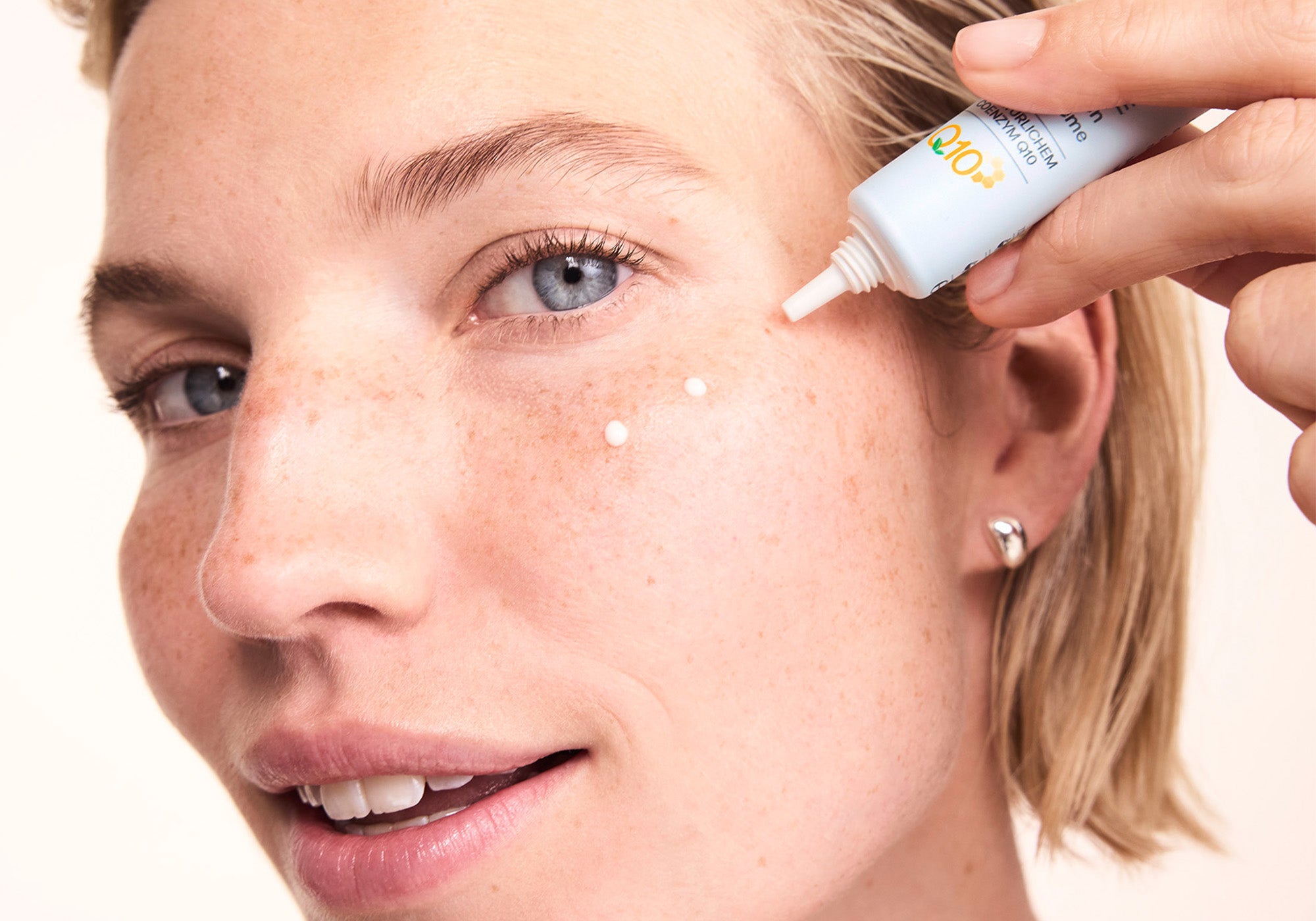 Frau trägt sich Augencreme Basis sensitive Q10 unter dem Auge auf