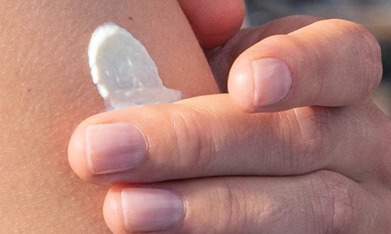 Nahaufnahme einer Hand, die Creme auf den Oberarm aufträgt