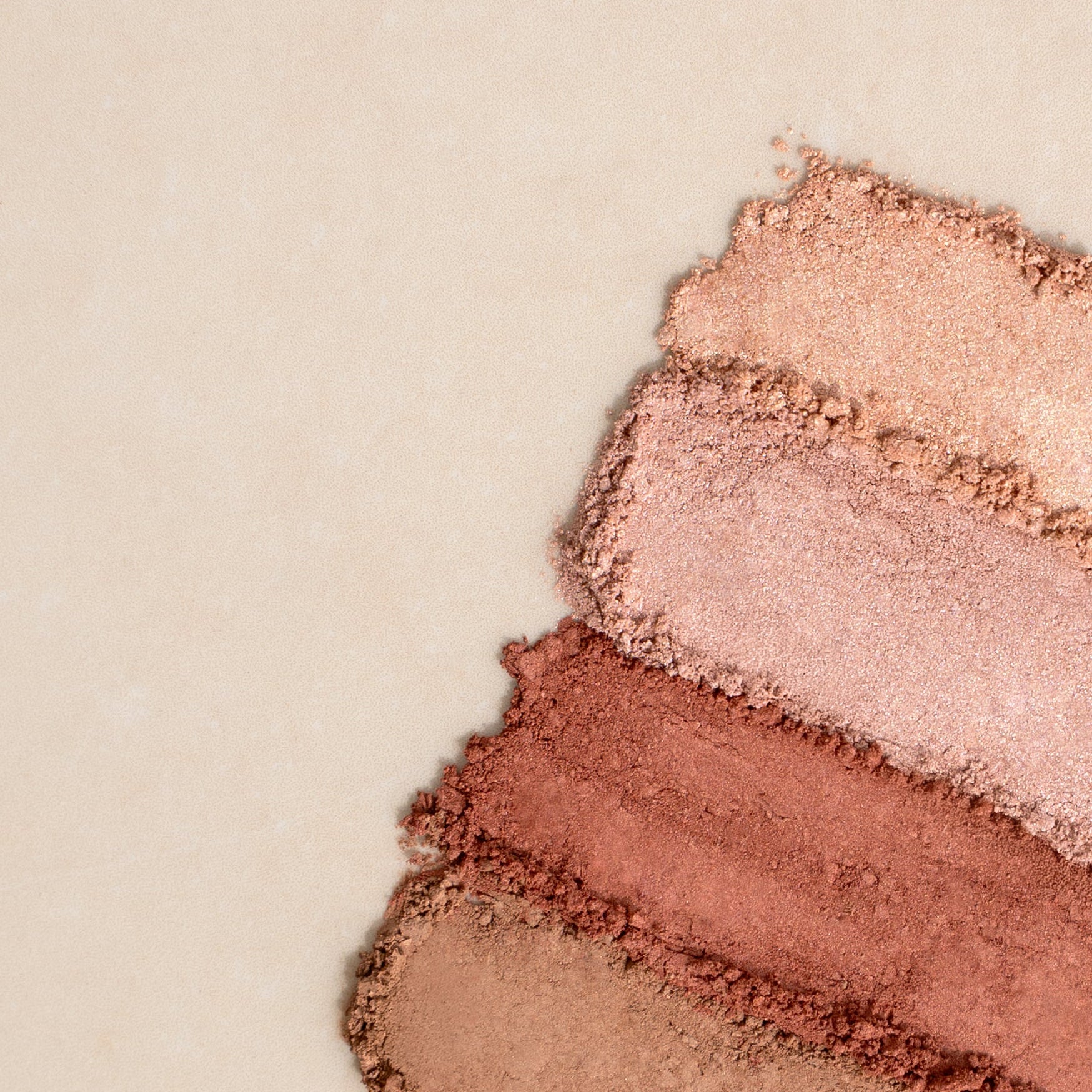 Drei Farb-Swatches von pudrigem Make-up in Nude-, Rosa- und Kupfertönen auf hellem Untergrund
