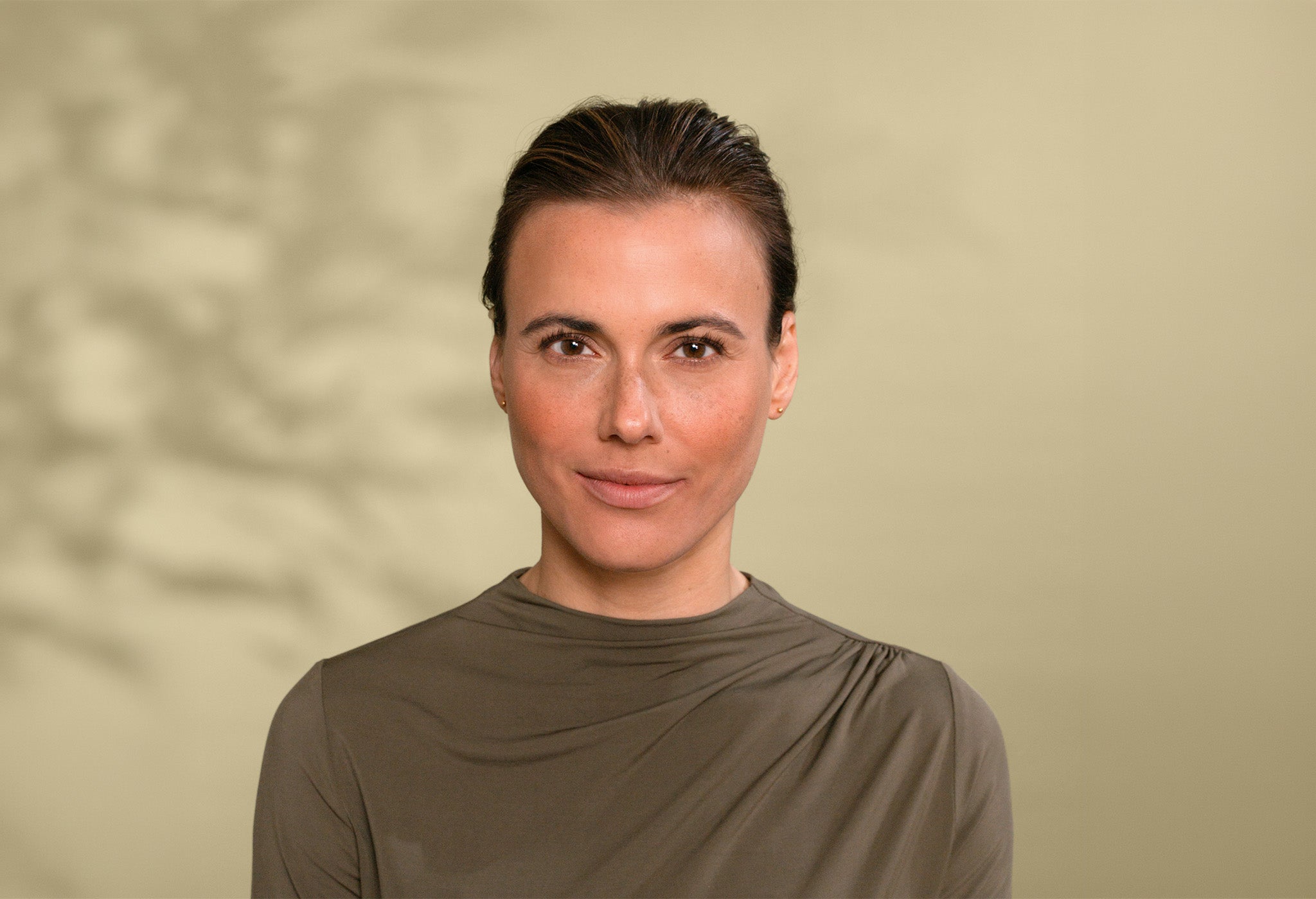 Portret kobiety z brązowymi oczami i brązowymi włosami na zielonym tle