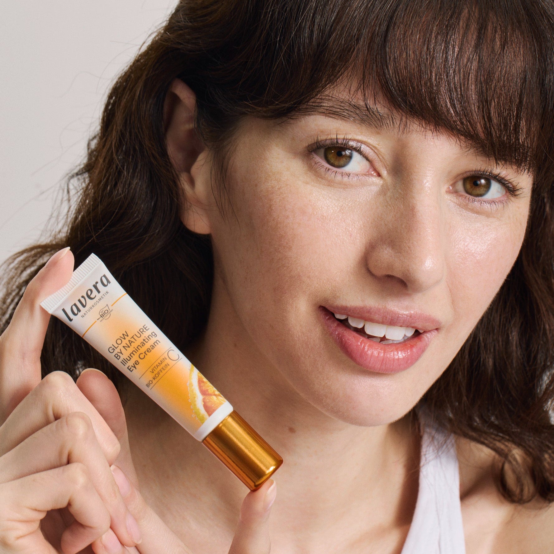 Kobieta trzyma w dłoni lavera Glow by Nature Illuminating Eye Cream