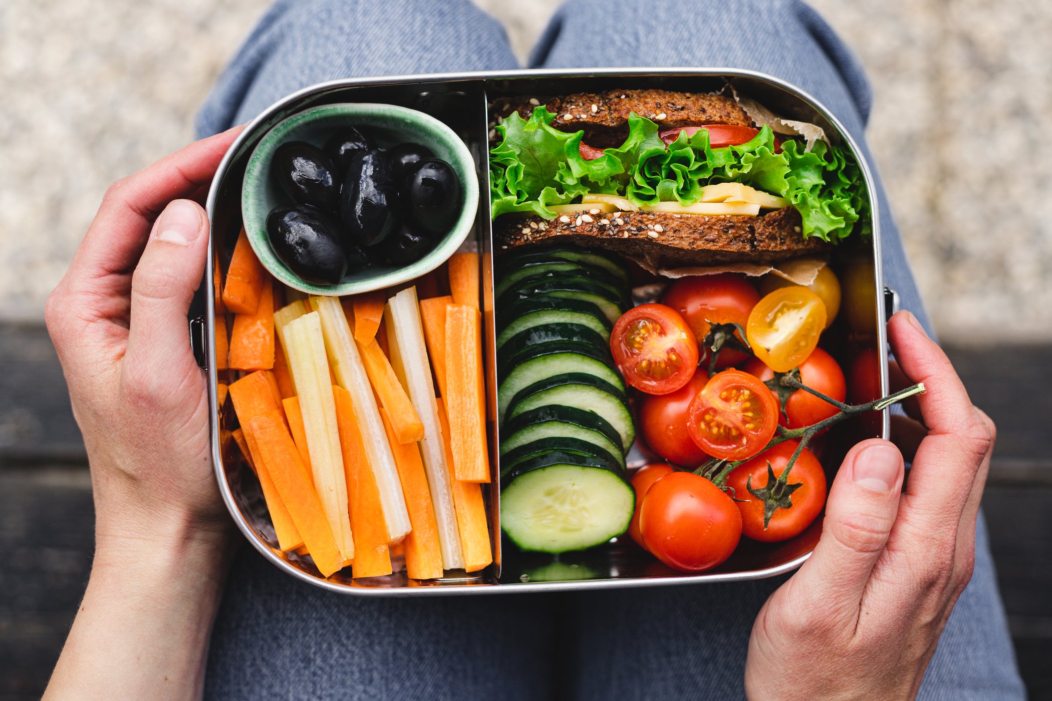 Pudełko bento z kanapką, marchewkami, ogórkiem, pomidorami i oliwkami, widok z góry