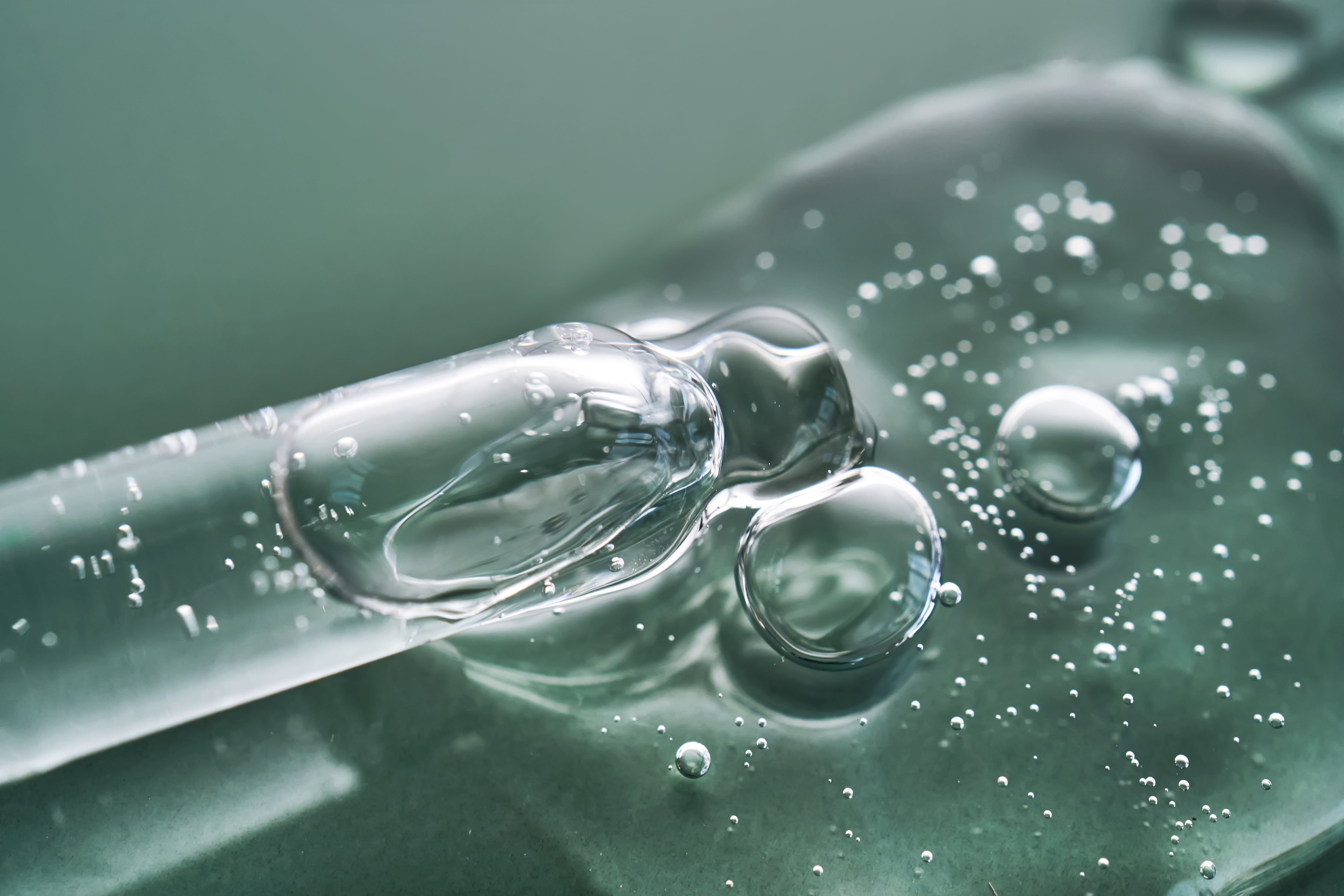 durchsichtige Flüssigkeit mit einer Pipette auf hellgrünen Hintergrund