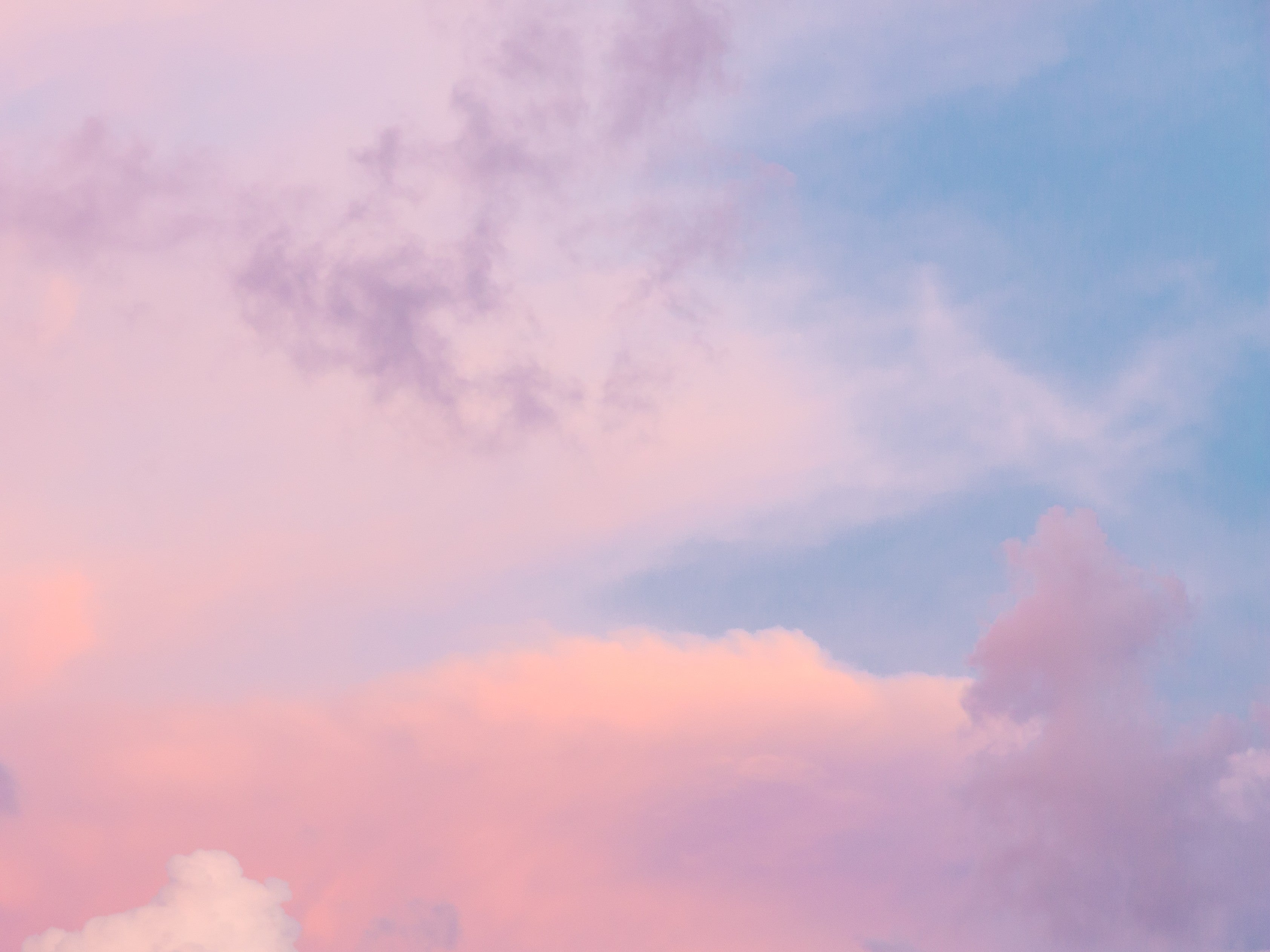 Zart rosa-blauer Himmel mit weichen Wolken bei Sonnenuntergang.