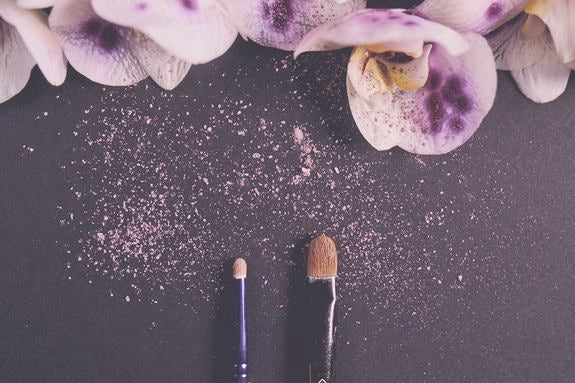 Zwei Lidschattenpinsel mit rosa Pigment und Blüten dekoriert