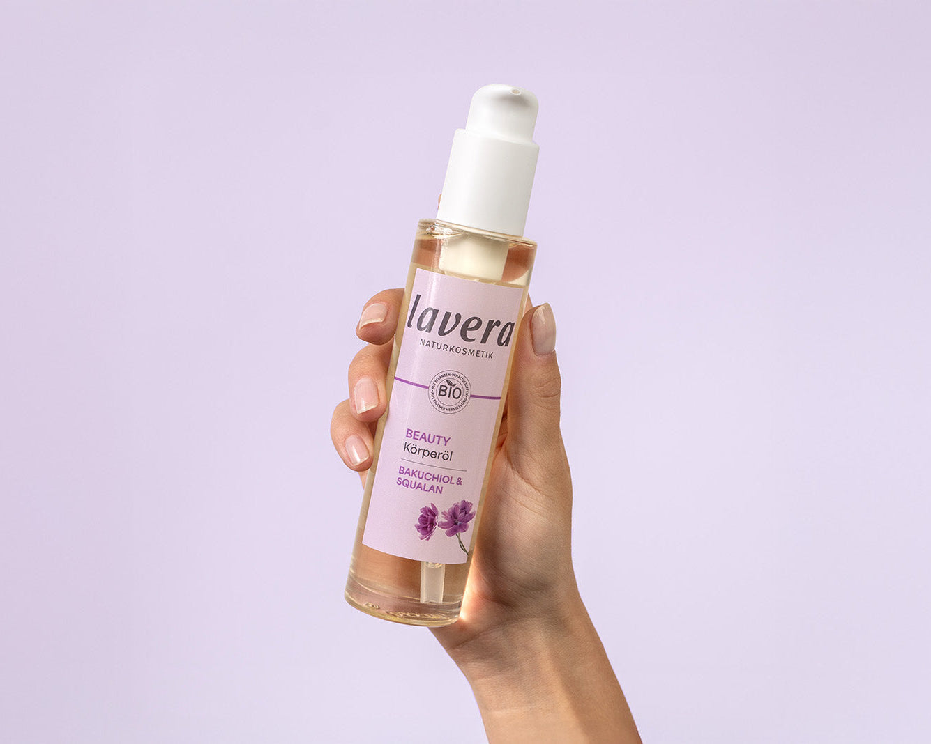 Hand, die Beauty Körperöl hält vor lila Hintergrund