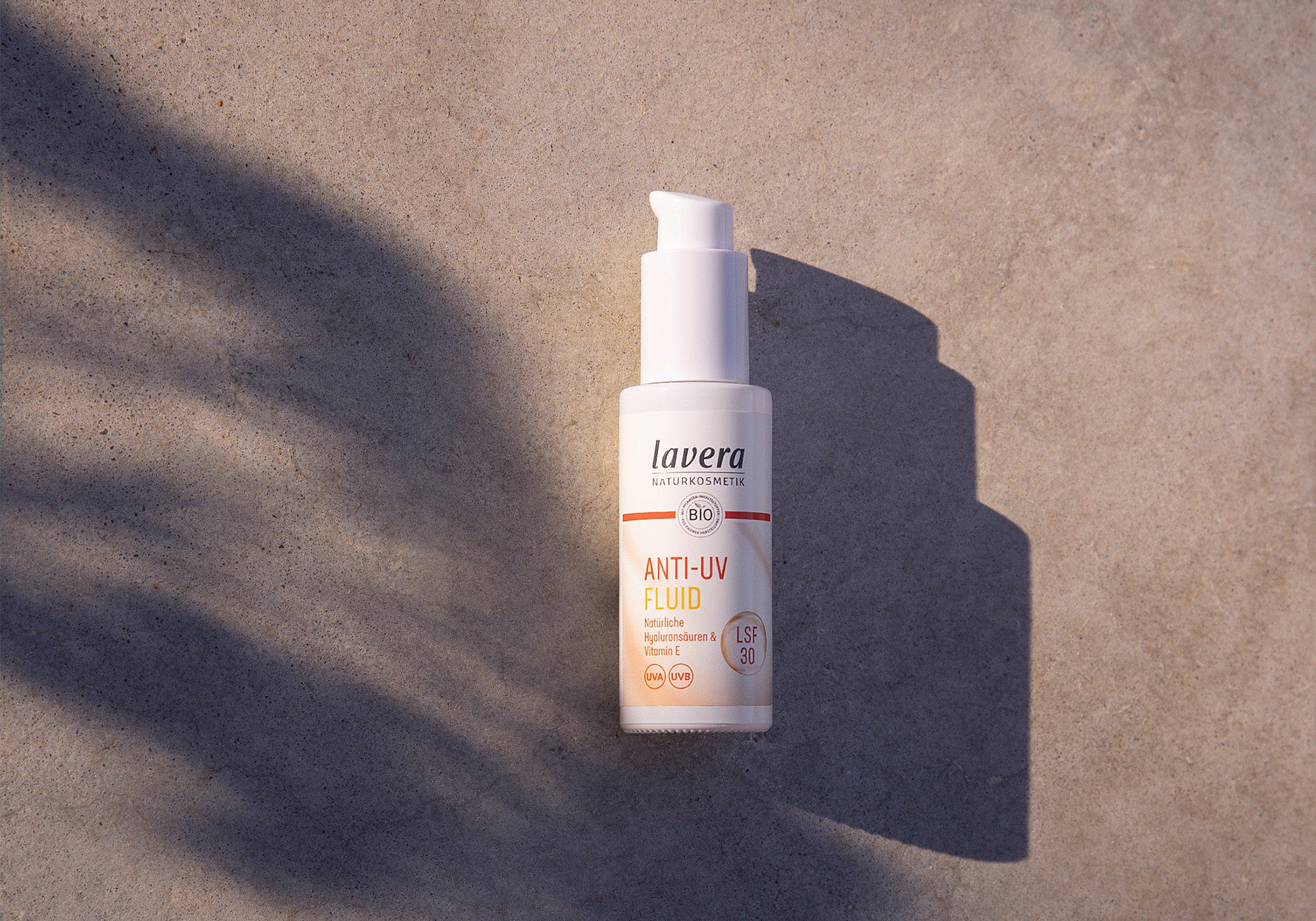 Anti UV Fluid auf grauem Hintergrund, auf den die Sonne scheint
