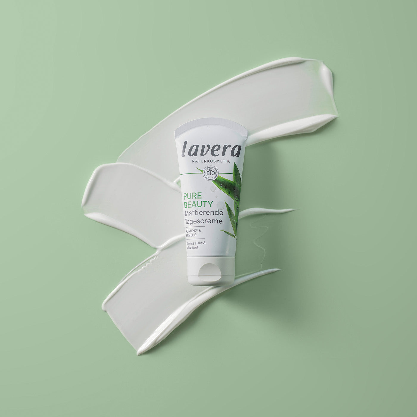 Zbliżenie Pure Beauty matujący krem na dzień przed białym kremowym zawijasem na zielonym tle