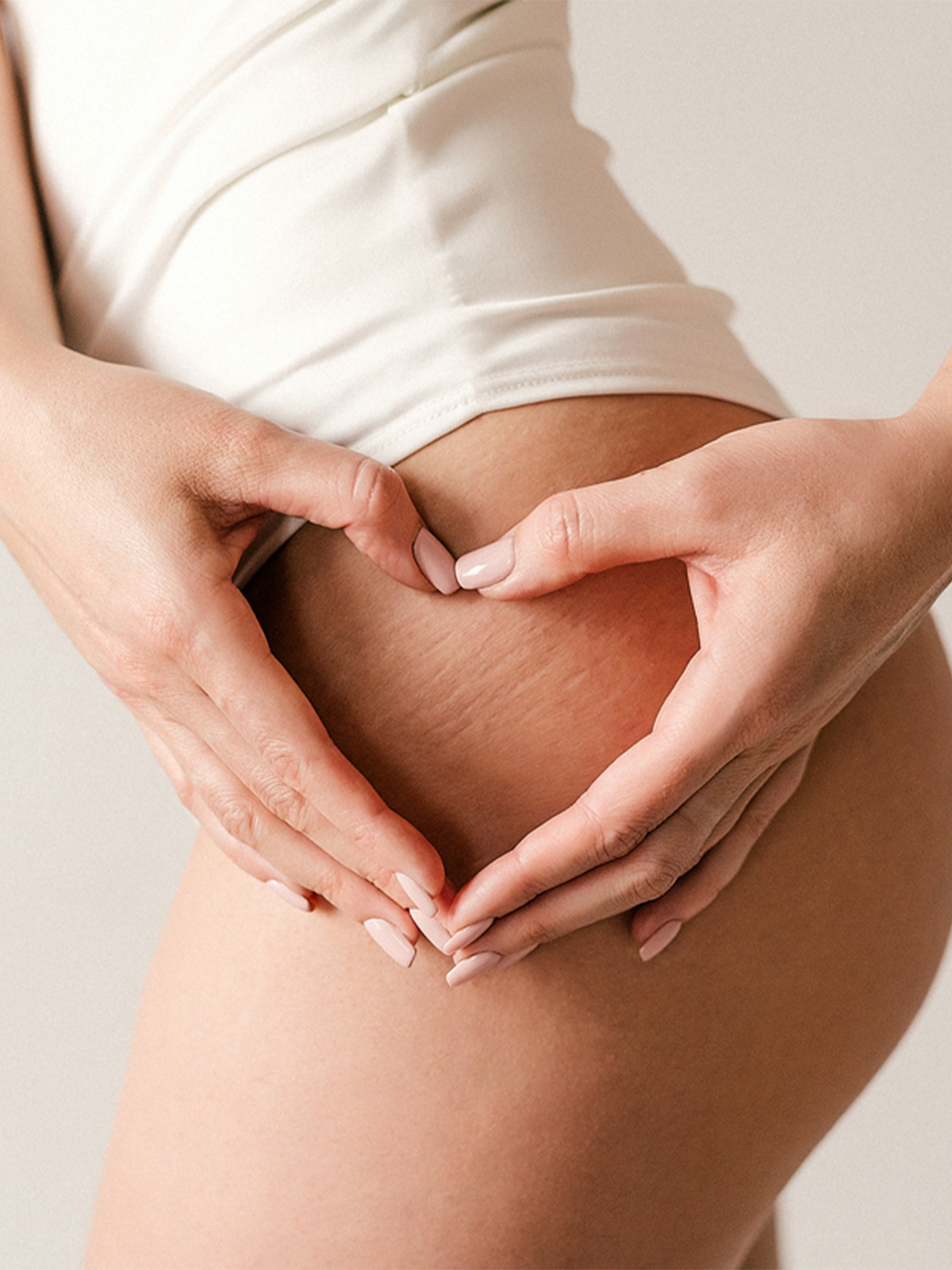 Frau formt mit ihren Händen ein Herz an ihrem Bein über den Cellulite Streifen