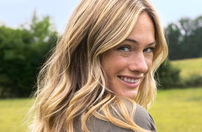 Blonde Frau lächelt über die Schulter im Grünen