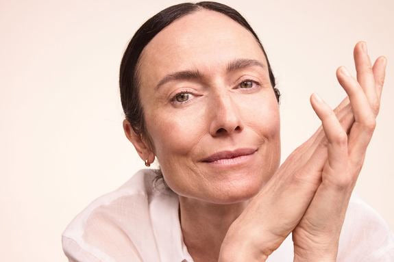 Dojrzała kobieta z włosami spiętymi do tyłu na ciepłym beżowym tle