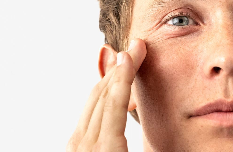 Mann trägt Pflegecreme auf die Wange auf